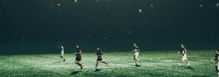 football match being played at night under floodlights